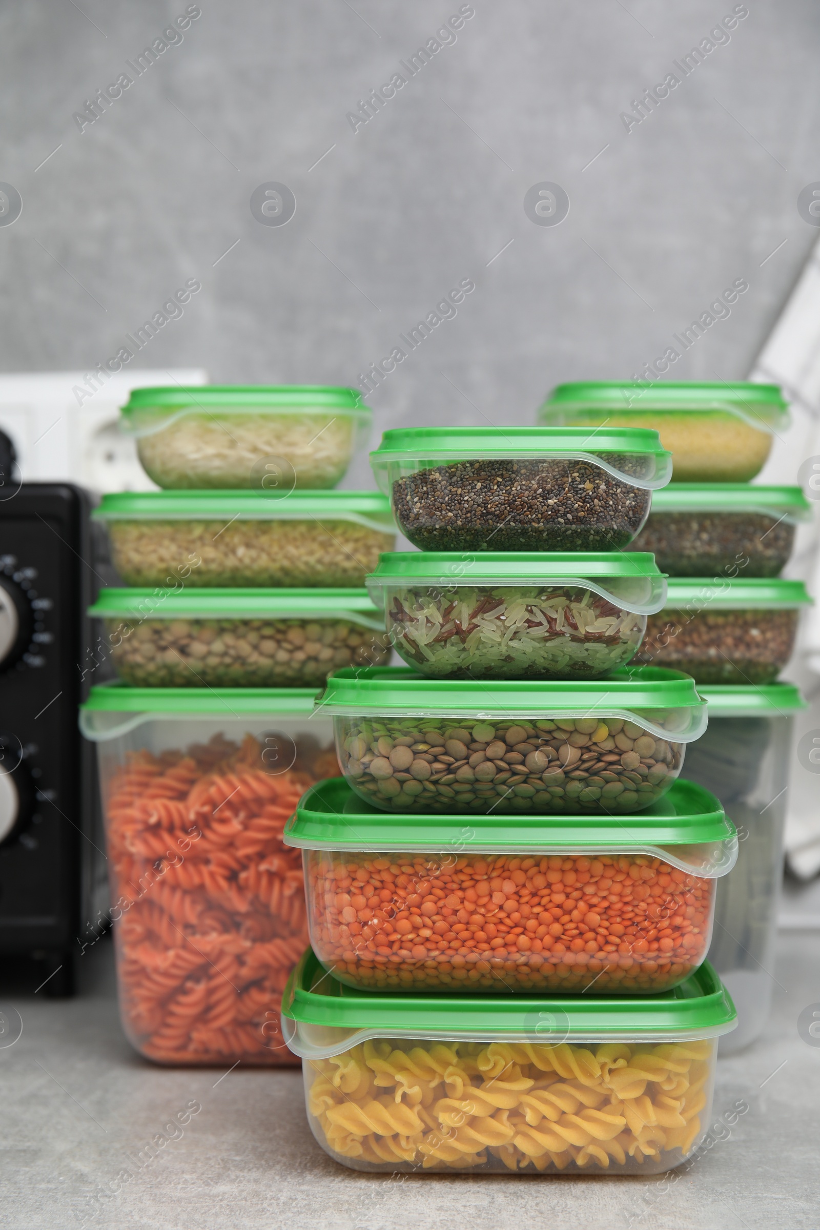 Photo of Plastic containers filled with food products on grey table in kitchen