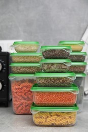 Photo of Plastic containers filled with food products on grey table in kitchen