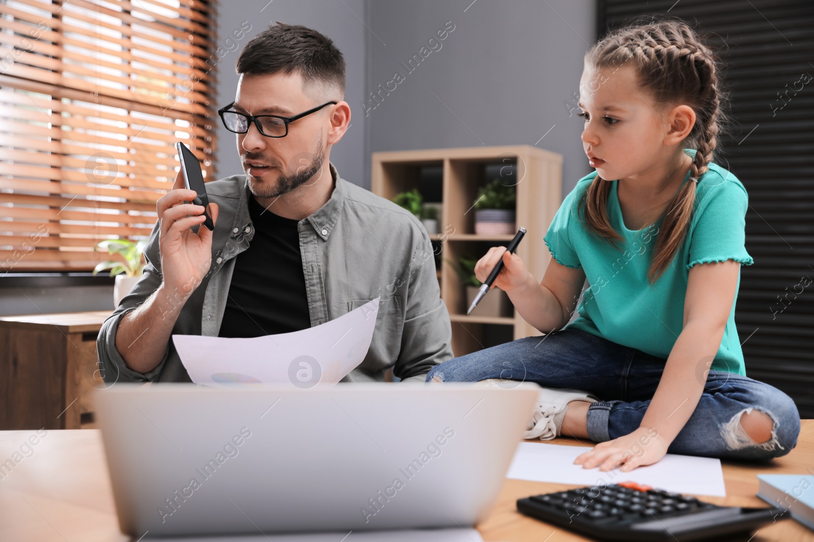 Photo of Overwhelmed man combining parenting and work at home