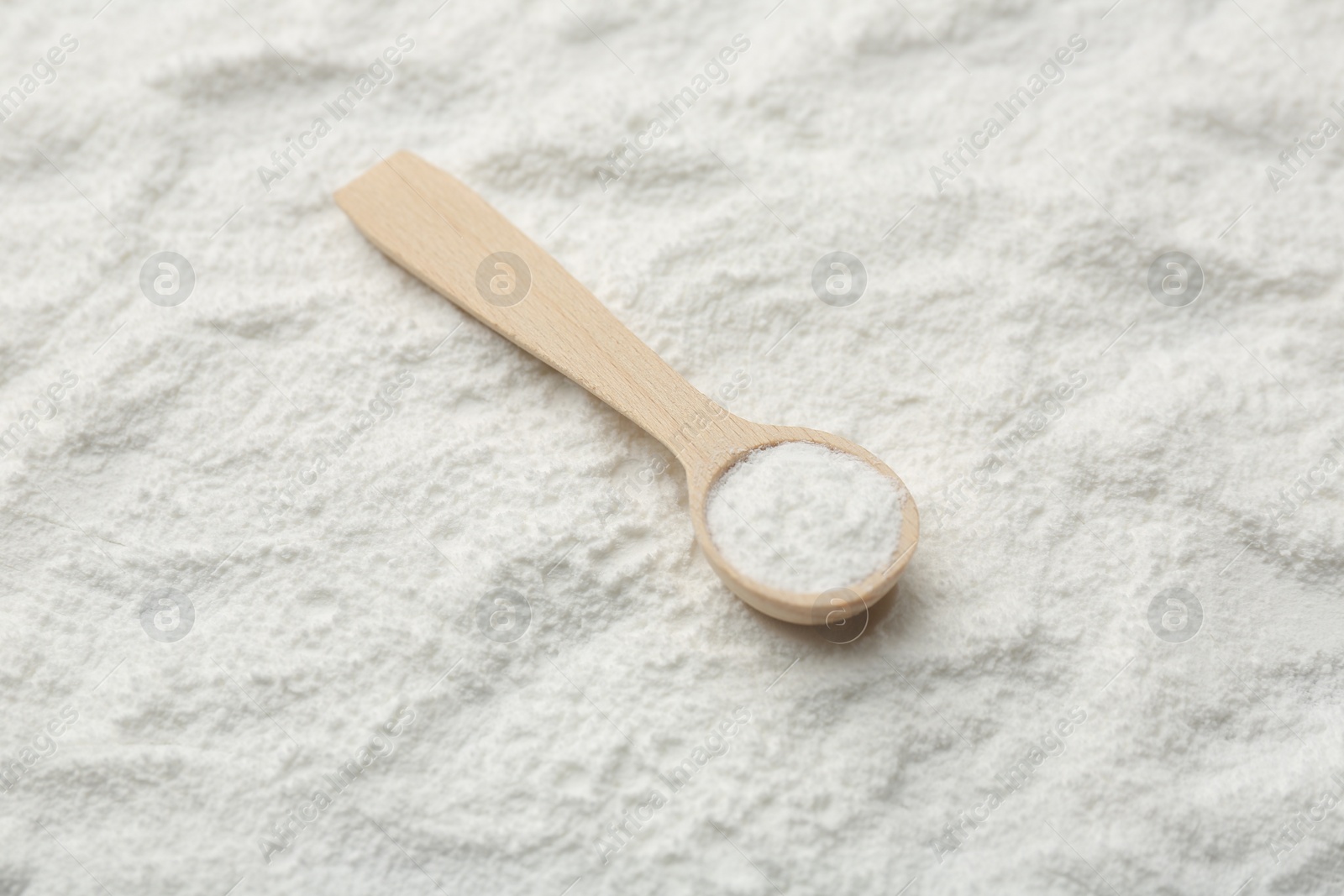 Photo of One wooden spoon on baking powder, closeup