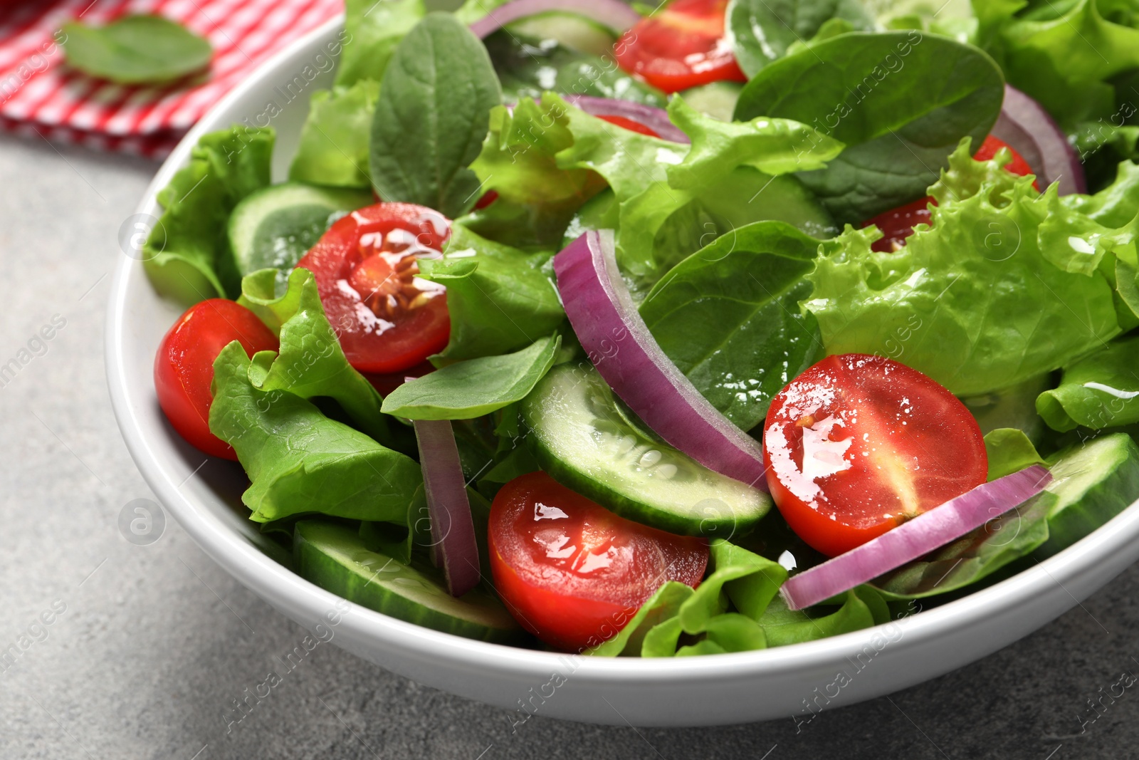 Photo of Delicious vegetable salad on light grey table, closeup