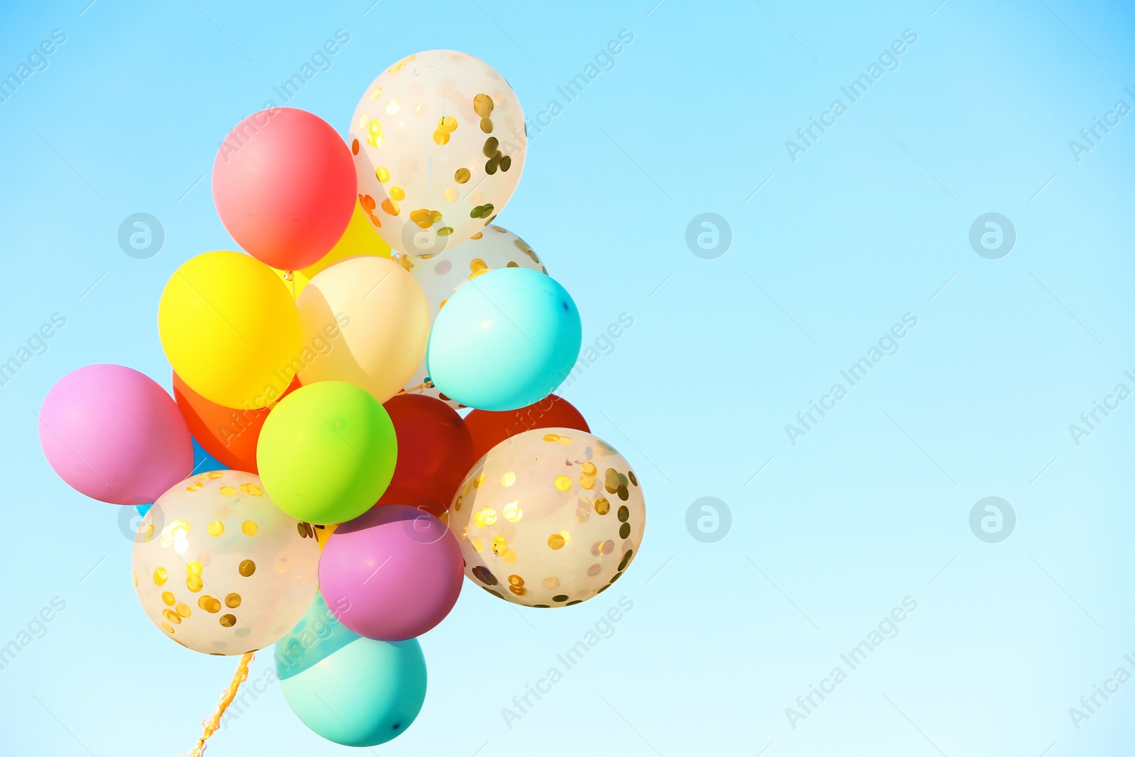 Photo of Many colorful balloons against blue sky on sunny day