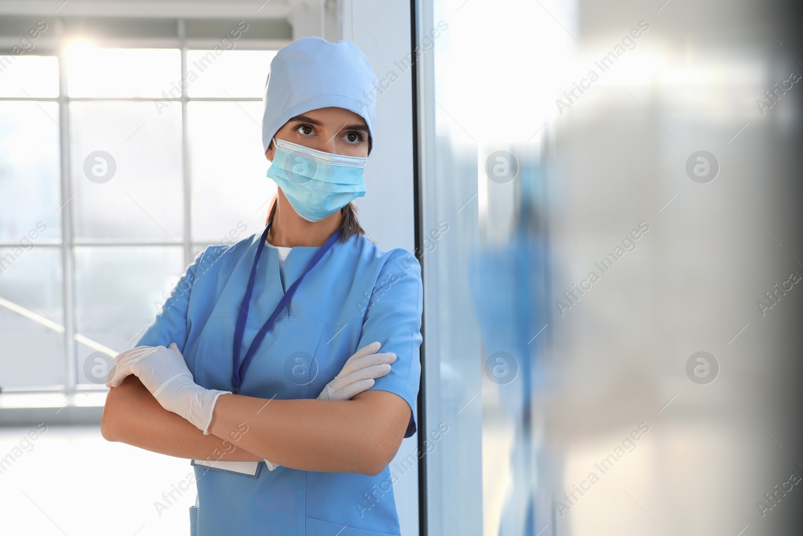 Photo of Doctor in medical gloves, protective mask and scrubs indoors. Space for text
