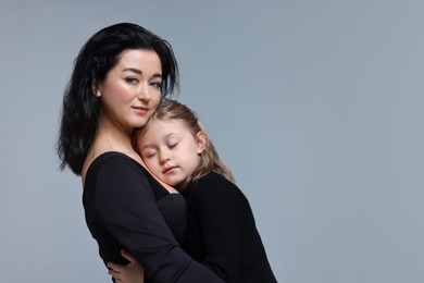 Photo of Beautiful mother hugging with little daughter on grey background. Space for text