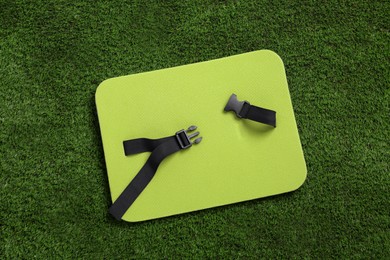 Photo of Bright foam seat mat for tourist on green grass, top view