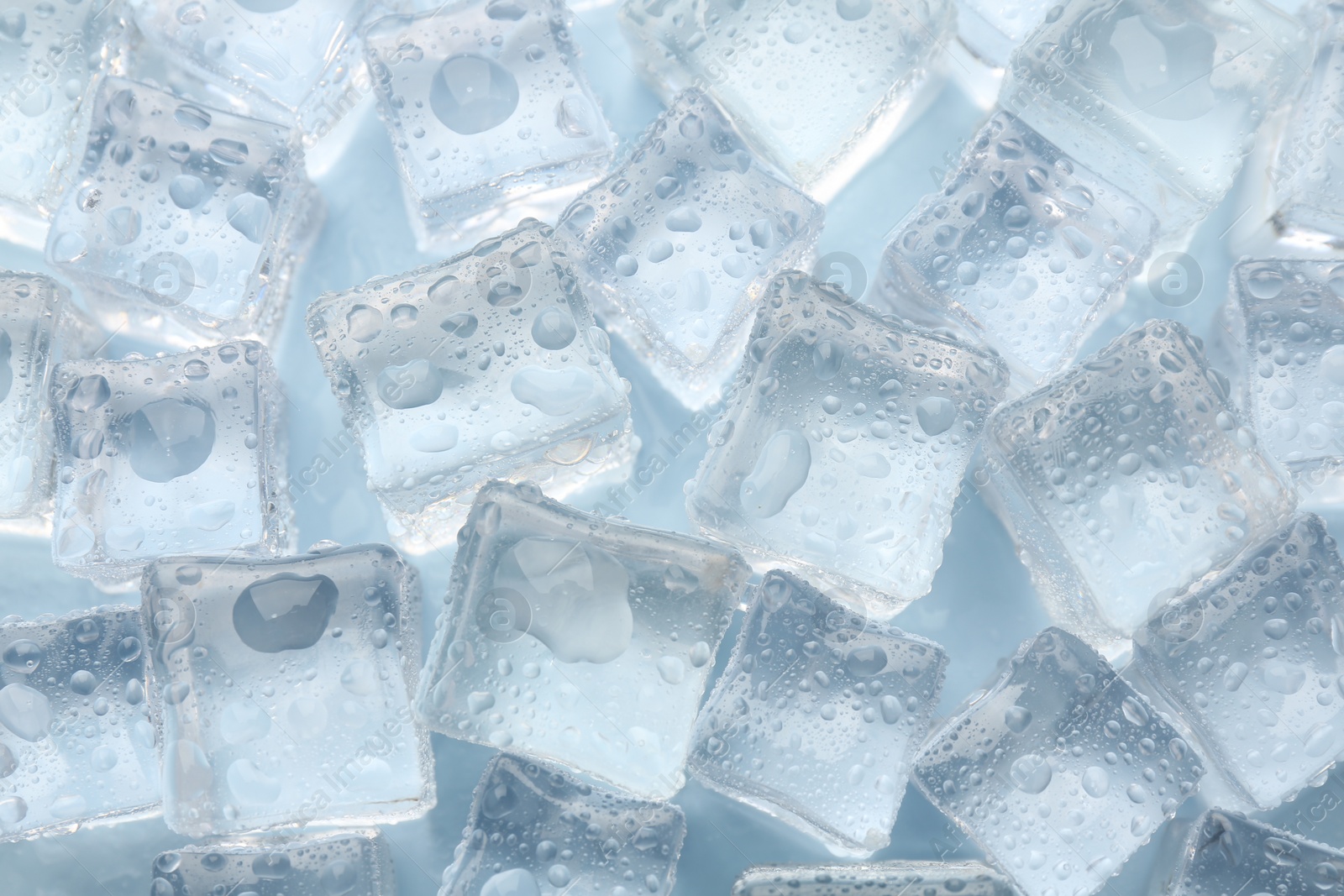 Photo of Crystal clear ice cubes on light blue background, flat lay