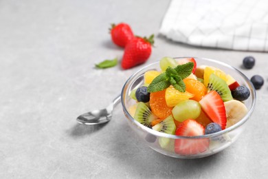 Photo of Delicious fresh fruit salad in bowl on light table, space for text