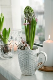 Beautiful bulbous plants and burning candles on windowsill indoors. Spring time