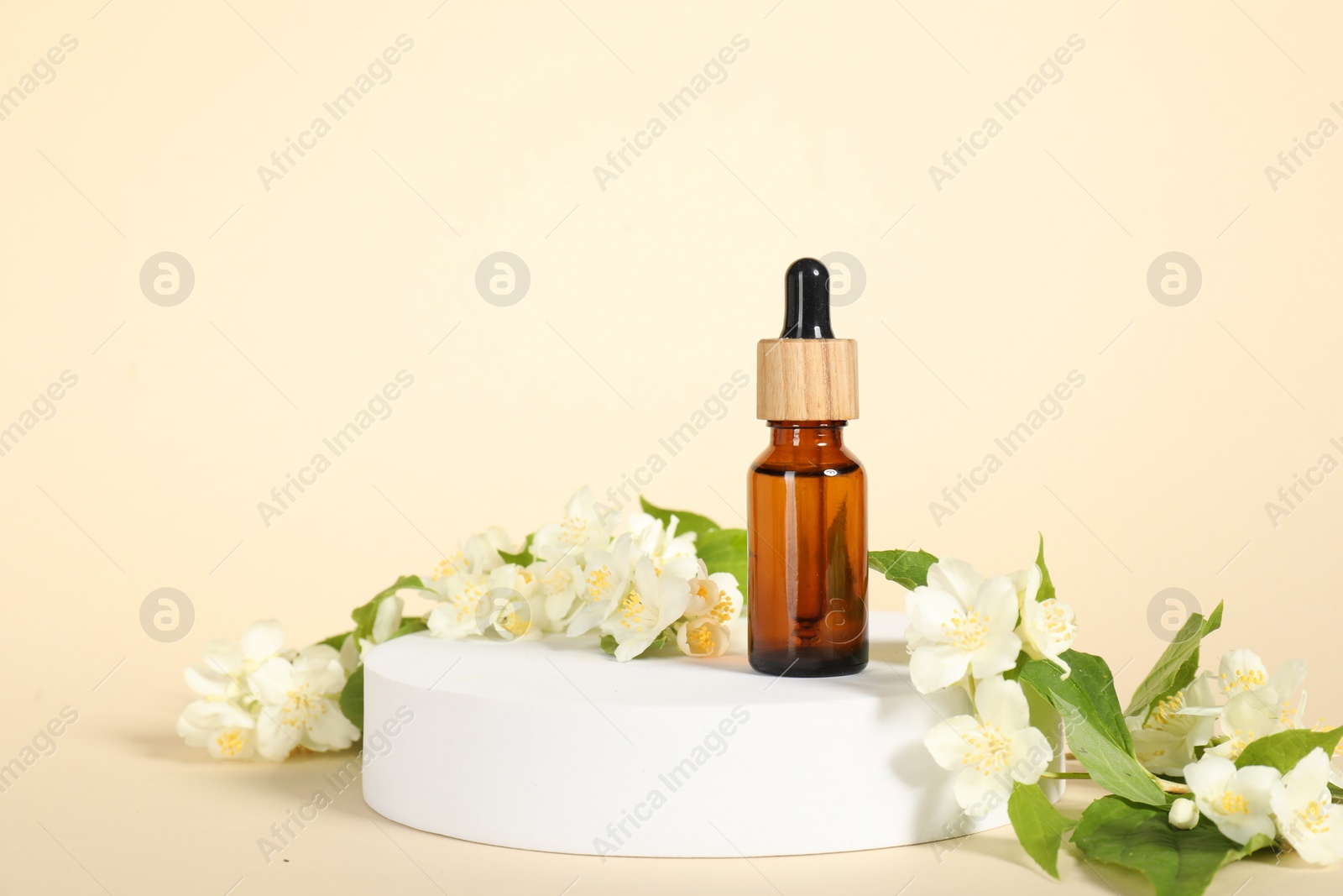 Photo of Presentation of essential oil in bottle and beautiful jasmine flowers against beige background, space for text