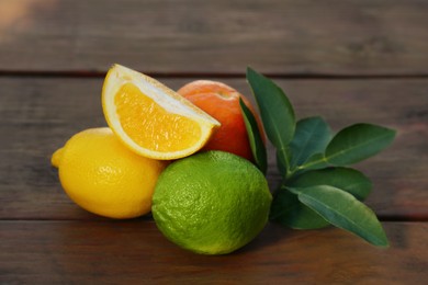 Photo of Different citrus fruits and leaves on wooden table