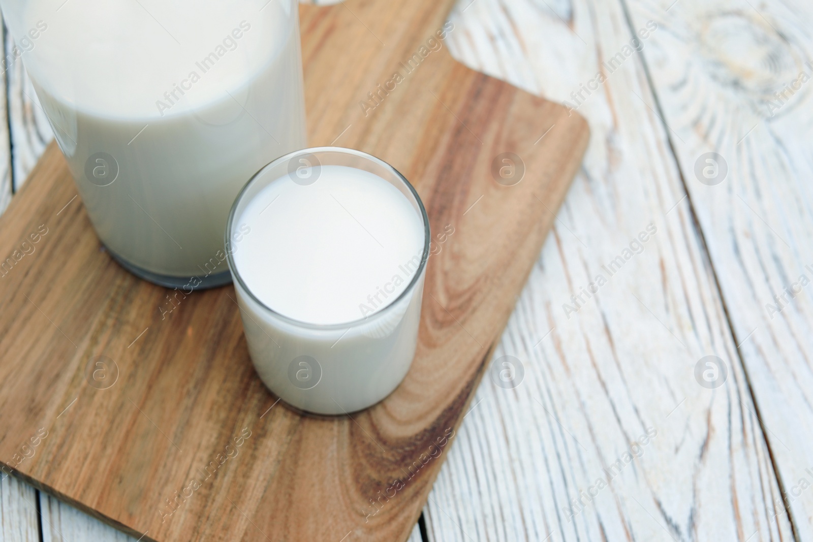 Photo of Bottle and glass of tasty fresh milk on white wooden table, closeup. Space for text