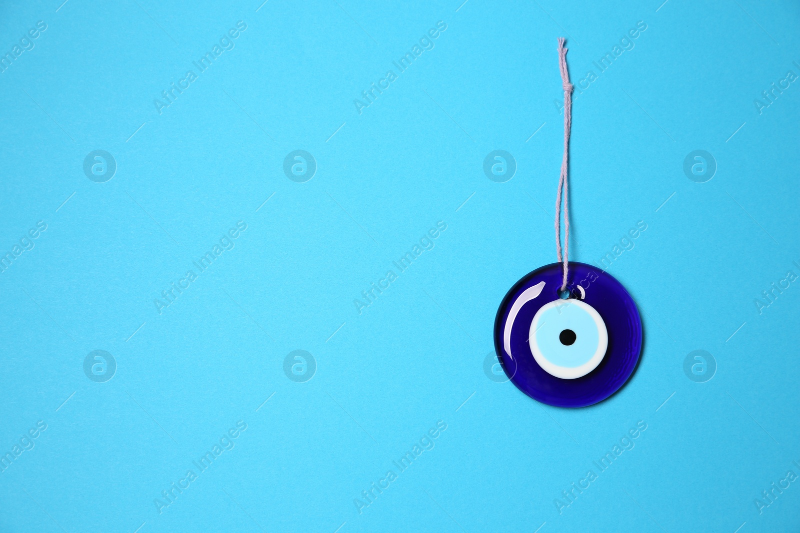 Photo of Evil eye amulet on light blue background, top view. Space for text