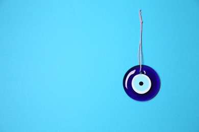 Photo of Evil eye amulet on light blue background, top view. Space for text