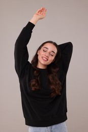 Beautiful young woman in stylish warm sweater on grey background