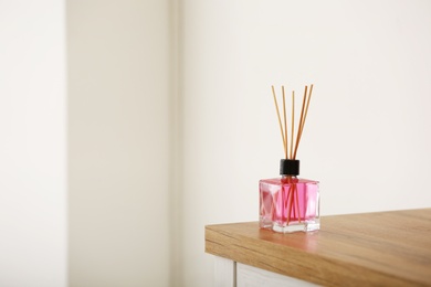 Photo of Aromatic reed air freshener on table against blurred background