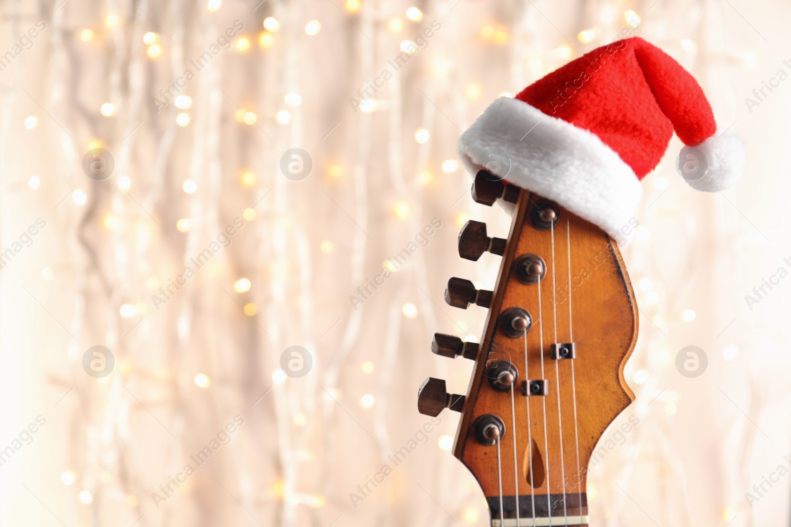 Photo of Guitar with Santa hat on blurred background. Christmas music concept