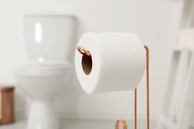 Photo of Holder with toilet paper roll in bathroom, closeup