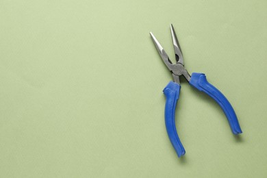 Needle nose pliers on olive background, top view. Space for text