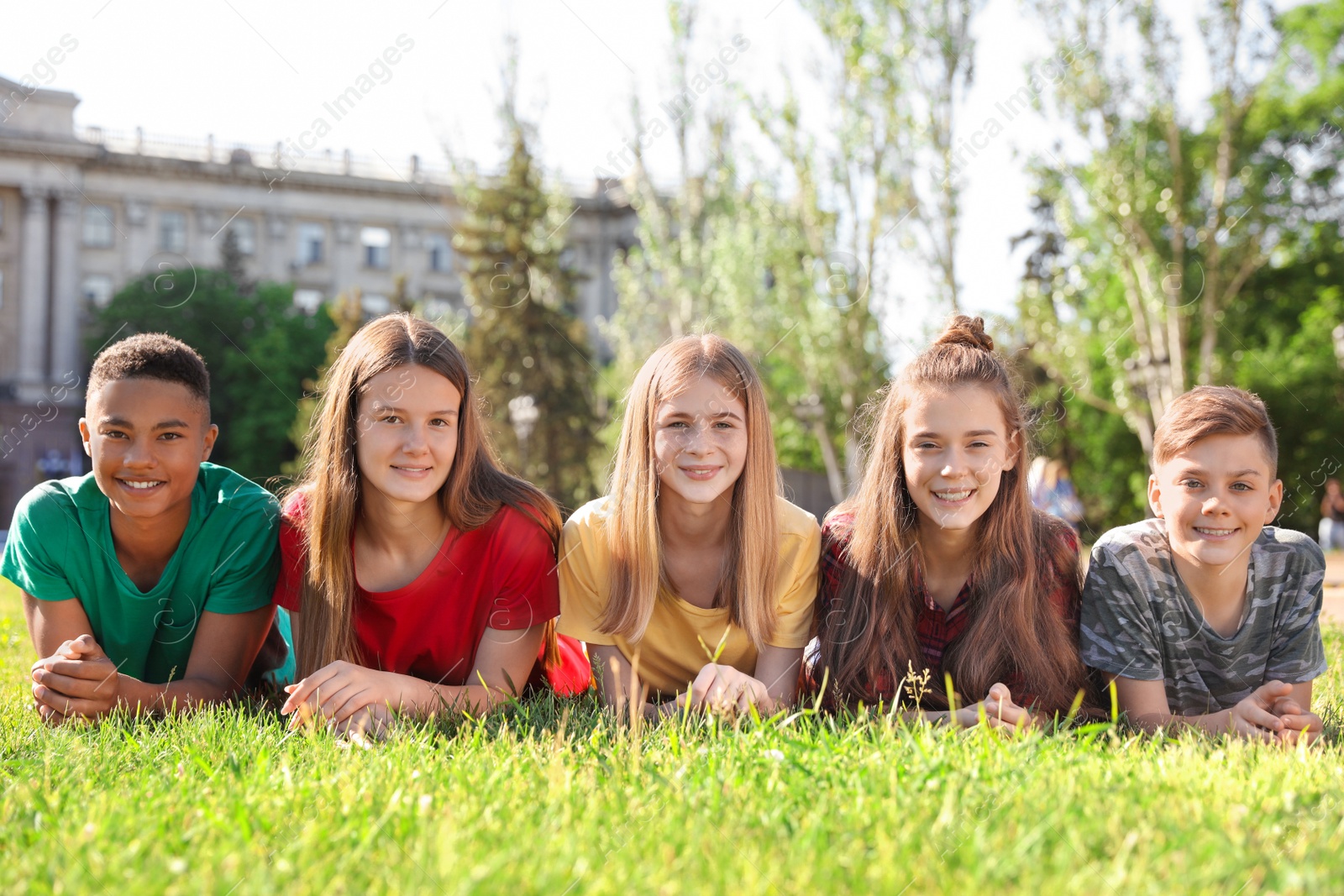 Photo of Group of children lying on grass outdoors. Summer camp