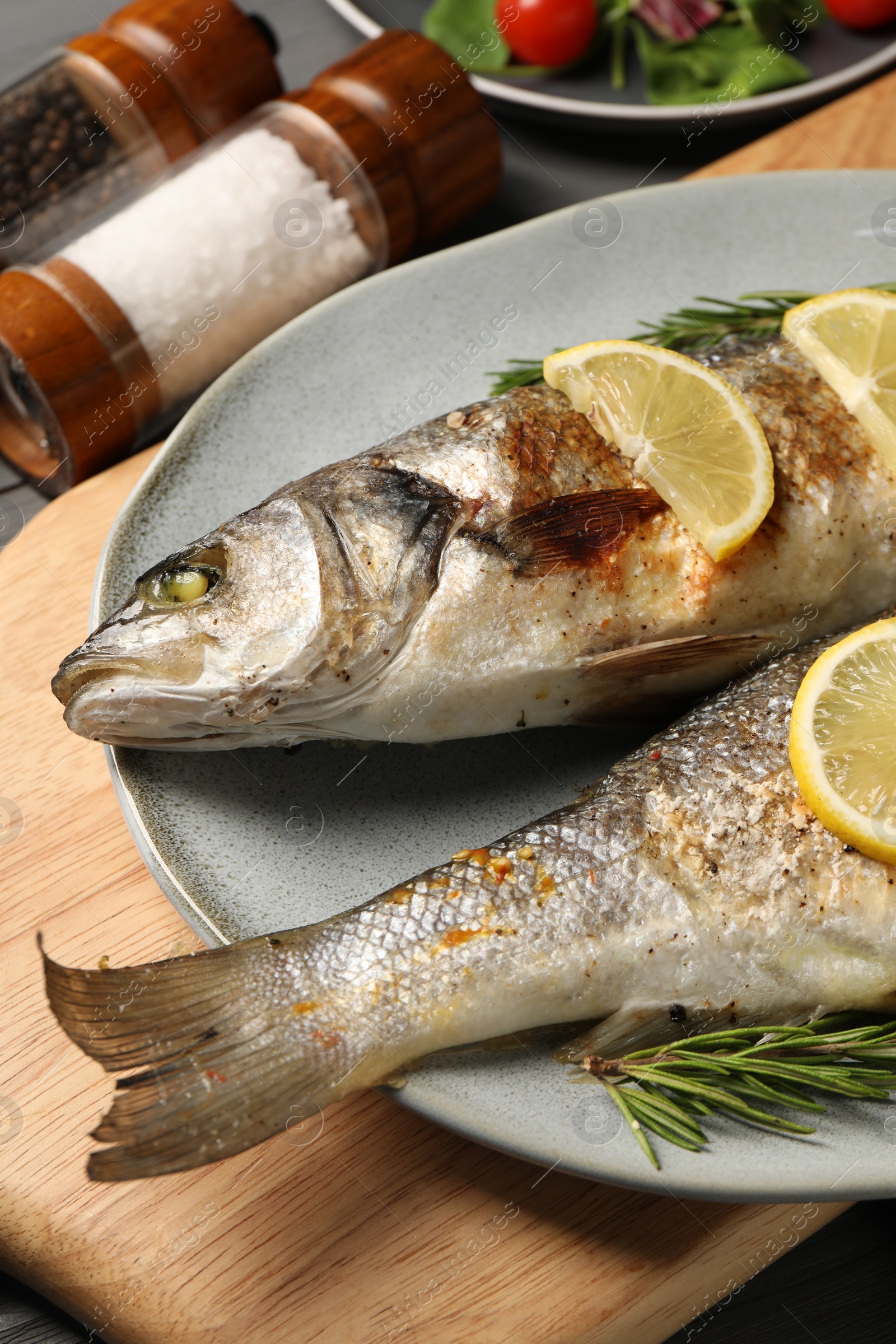 Photo of Delicious baked fish, lemon and rosemary on table, closeup