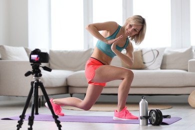 Smiling sports blogger recording fitness lesson with camera at home