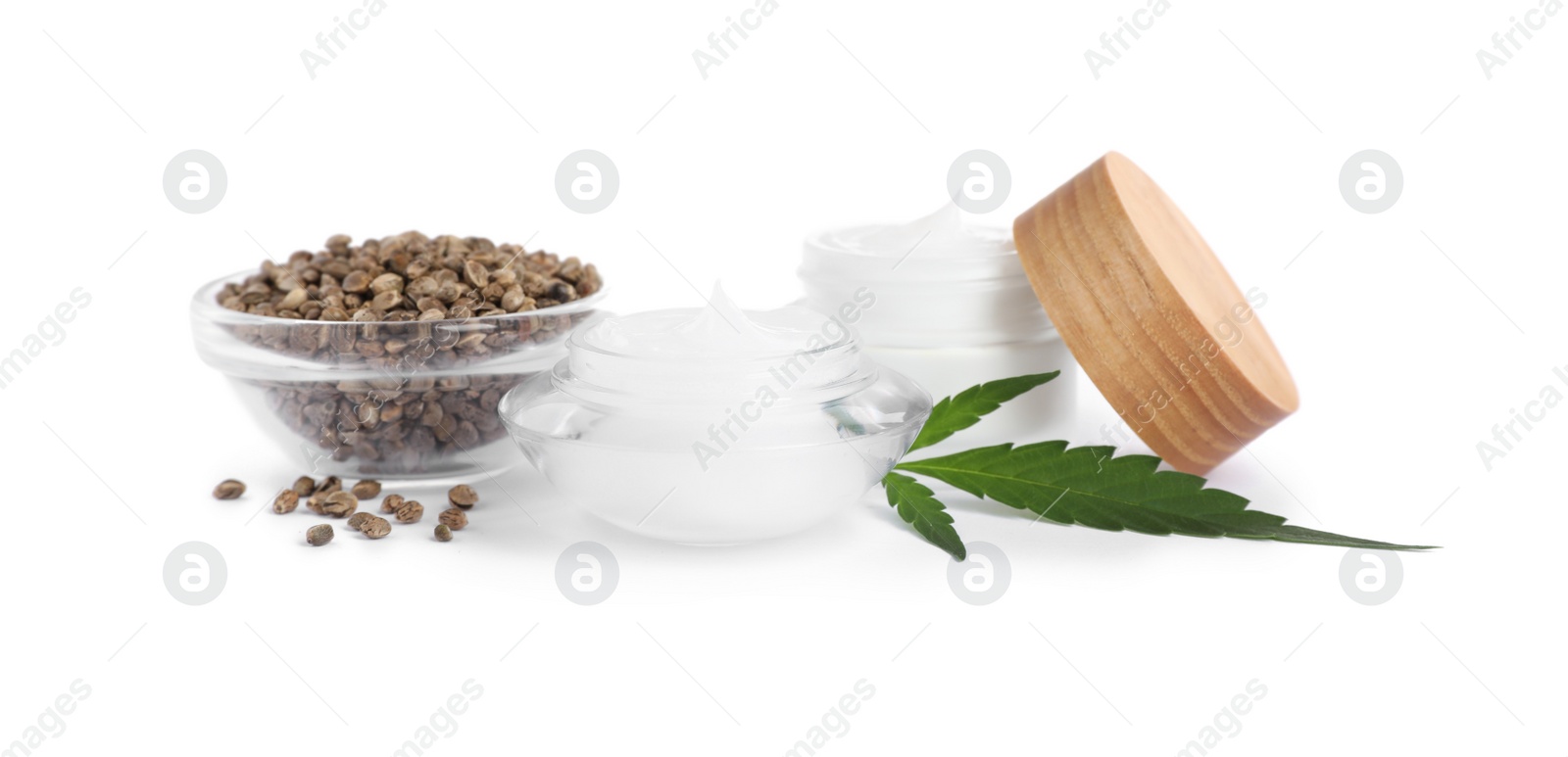 Photo of Jars with hemp cream, seeds and green leaf on white background. Natural cosmetics