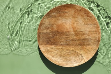 Photo of Presentation of product. Wooden podium in water on green background, top view. Space for text