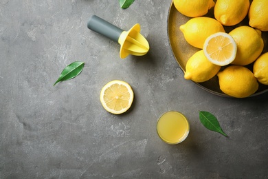 Photo of Flat lay composition with ripe lemons and glass of juice on grey background