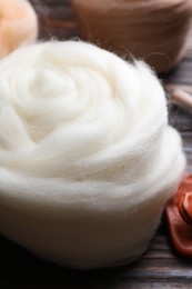 Photo of White felting wool on wooden table, closeup
