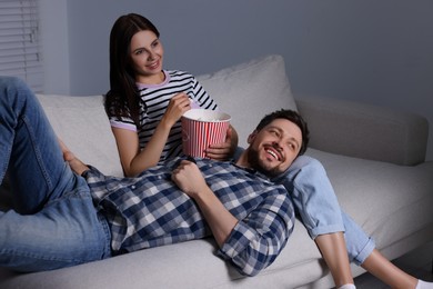 Happy couple watching TV at home in evening
