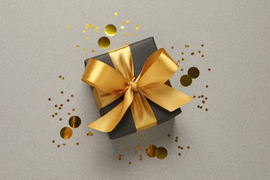 Photo of Beautiful gift box and confetti on grey background, flat lay