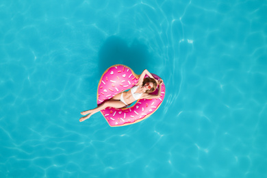 Young happy woman with inflatable ring in swimming pool, top view. Summer vacation