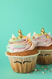 Photo of Cute sweet unicorn cupcakes on turquoise background, closeup