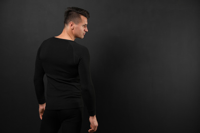 Photo of Man wearing thermal underwear on black background. Space for text