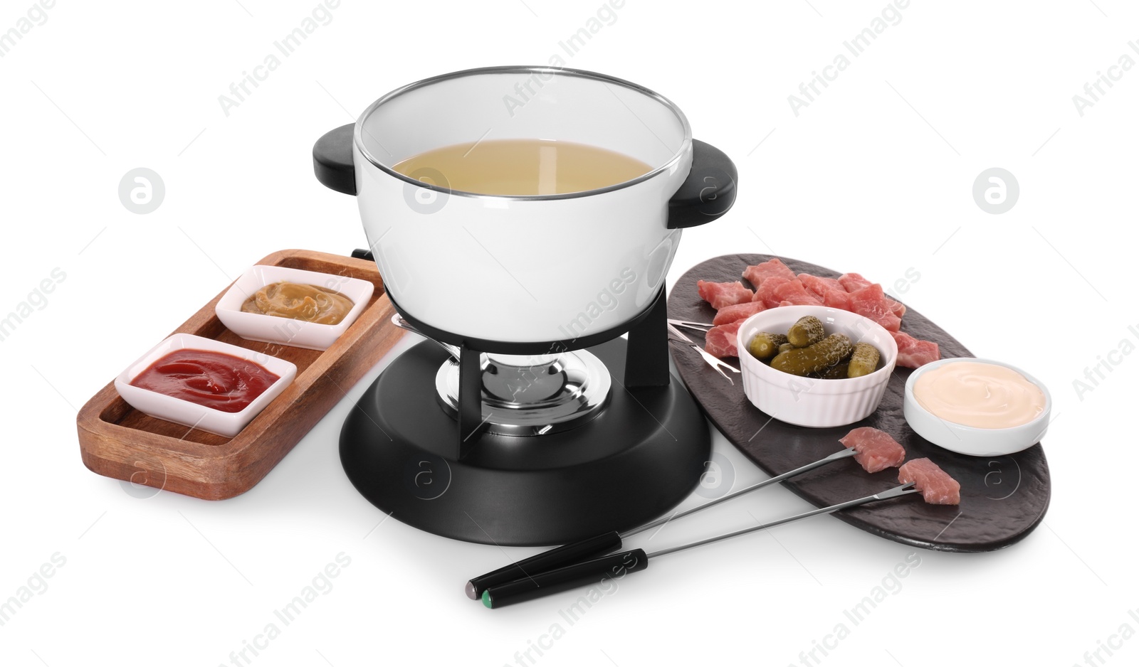 Photo of Oil in fondue pot, forks, pickles, sauces and pieces of raw meat isolated on white