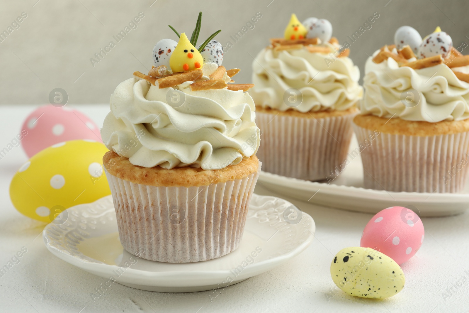 Photo of Tasty Easter cupcakes with vanilla cream on white table, closeup