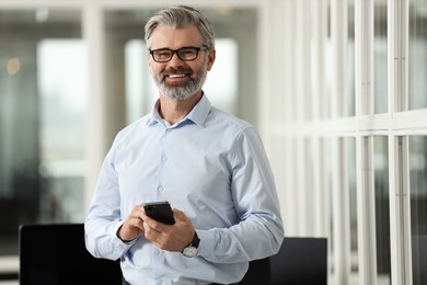 Smiling man with smartphone in office. Lawyer, businessman, accountant or manager