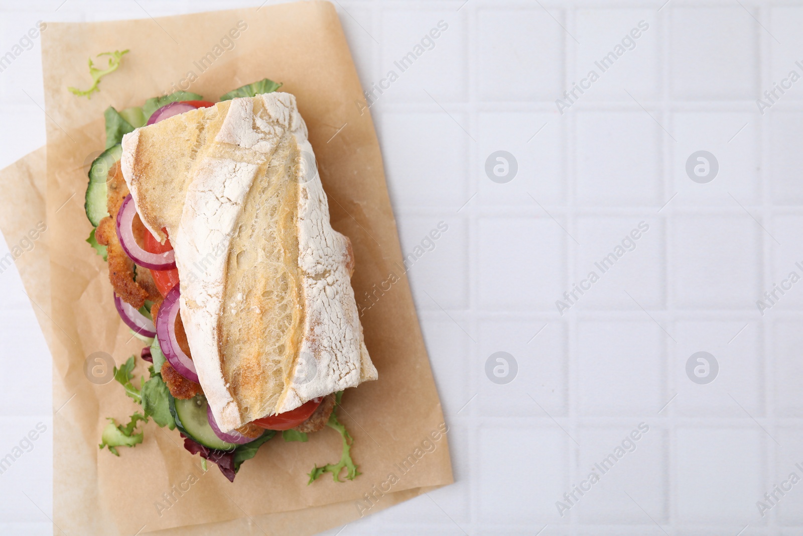 Photo of Delicious sandwich with schnitzel on white tiled table, top view. Space for text