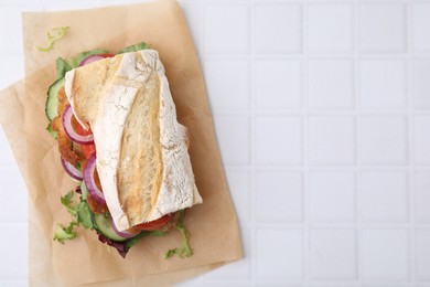 Delicious sandwich with schnitzel on white tiled table, top view. Space for text