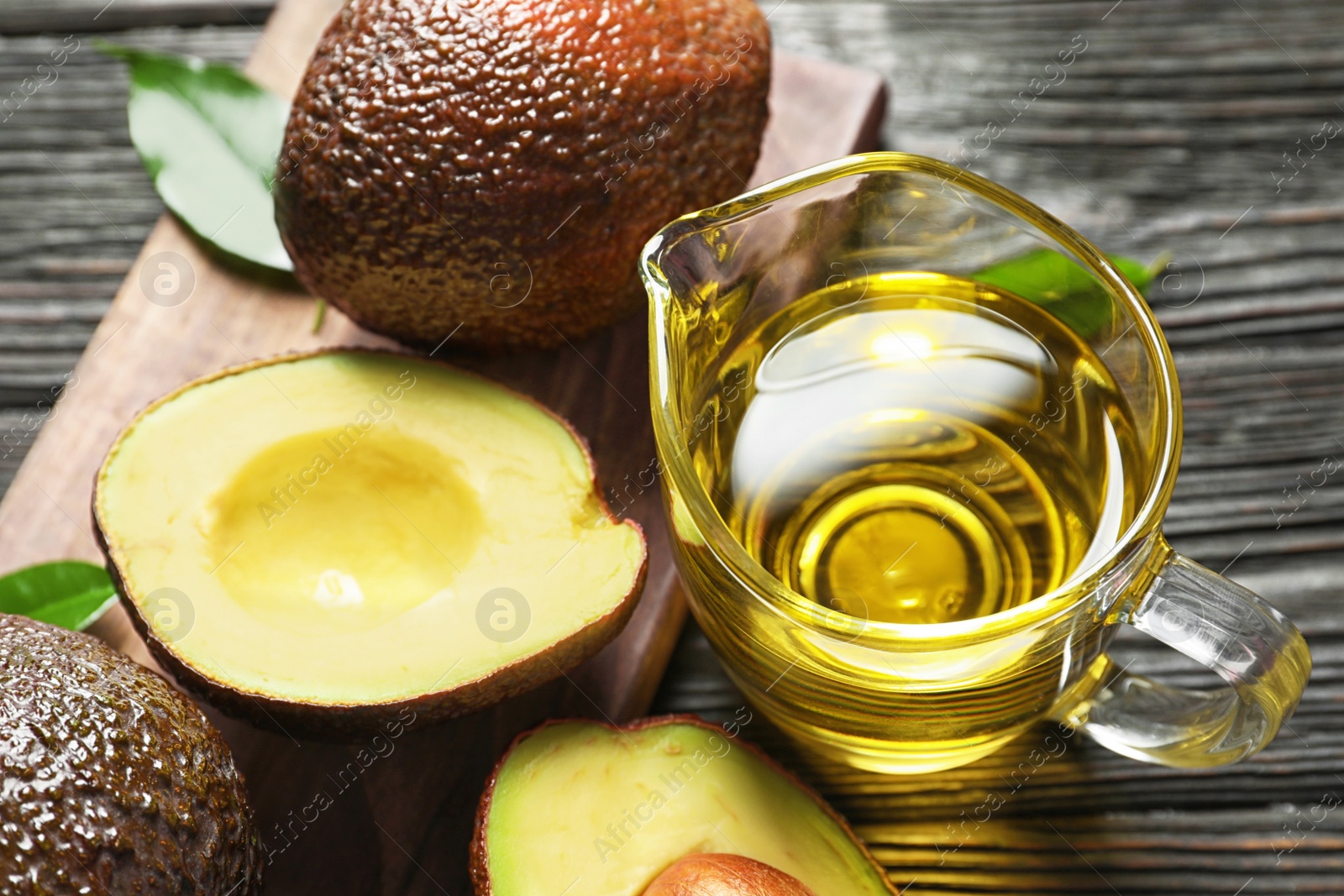 Photo of Gravy boat with oil and ripe fresh avocados, closeup