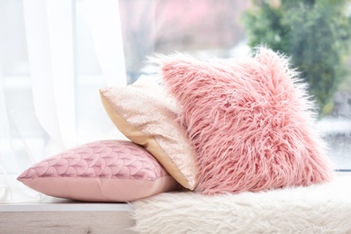 Photo of Different soft pillows on windowsill