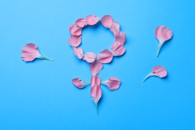 Photo of Female gender sign made of petals on light blue background, top view. Women's health concept