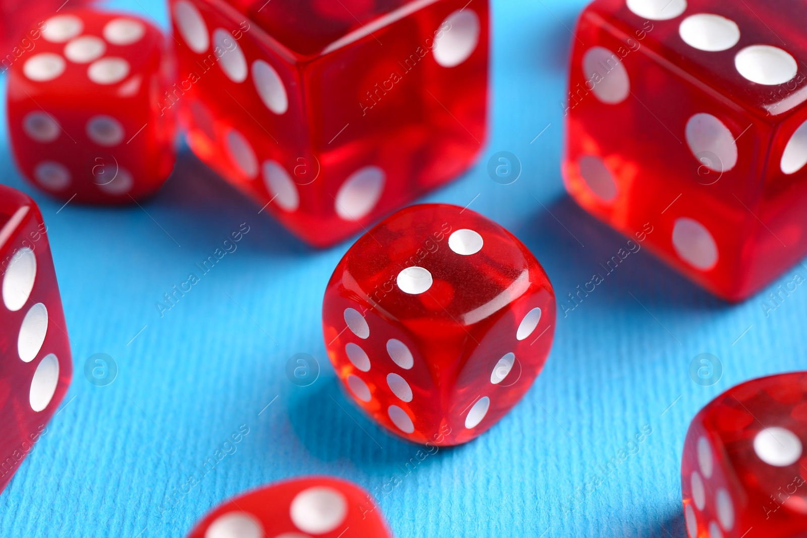 Photo of Many red game dices on light blue background, closeup