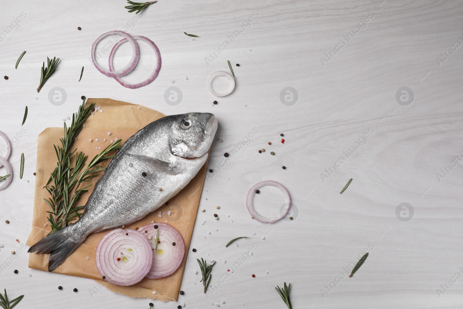 Photo of Raw dorado fish, spices and onion on white wooden table, flat lay