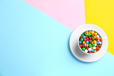Photo of Cup with delicious bright glazed candies on color background, top view. Space for text