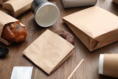 Paper bags and different takeaway items on wooden table. Space for design