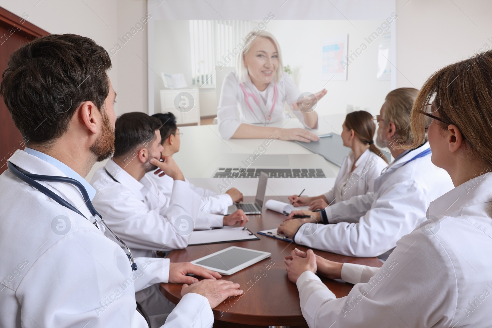 Image of Lecture with online participant. Doctors in meeting room. Using projector for videoconference