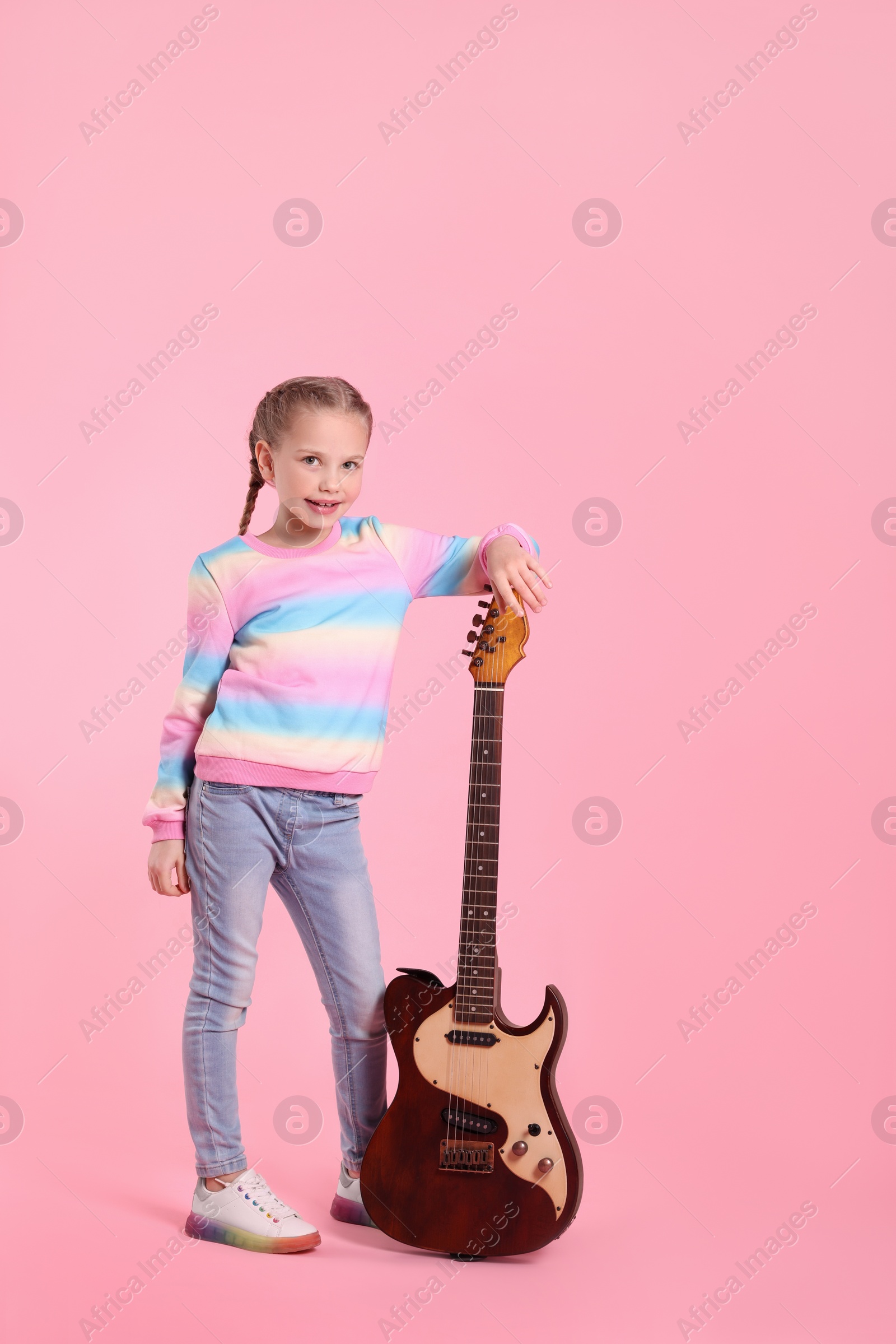 Photo of Cute girl with electric guitar on pink background