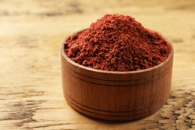 Photo of Cranberry powder in bowl on wooden table, closeup