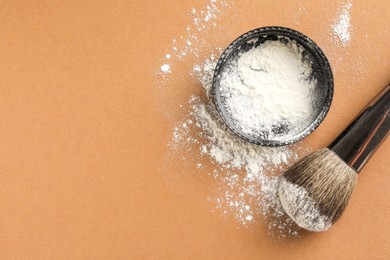 Photo of Rice loose face powder and makeup brush on brown background, flat lay. Space for text